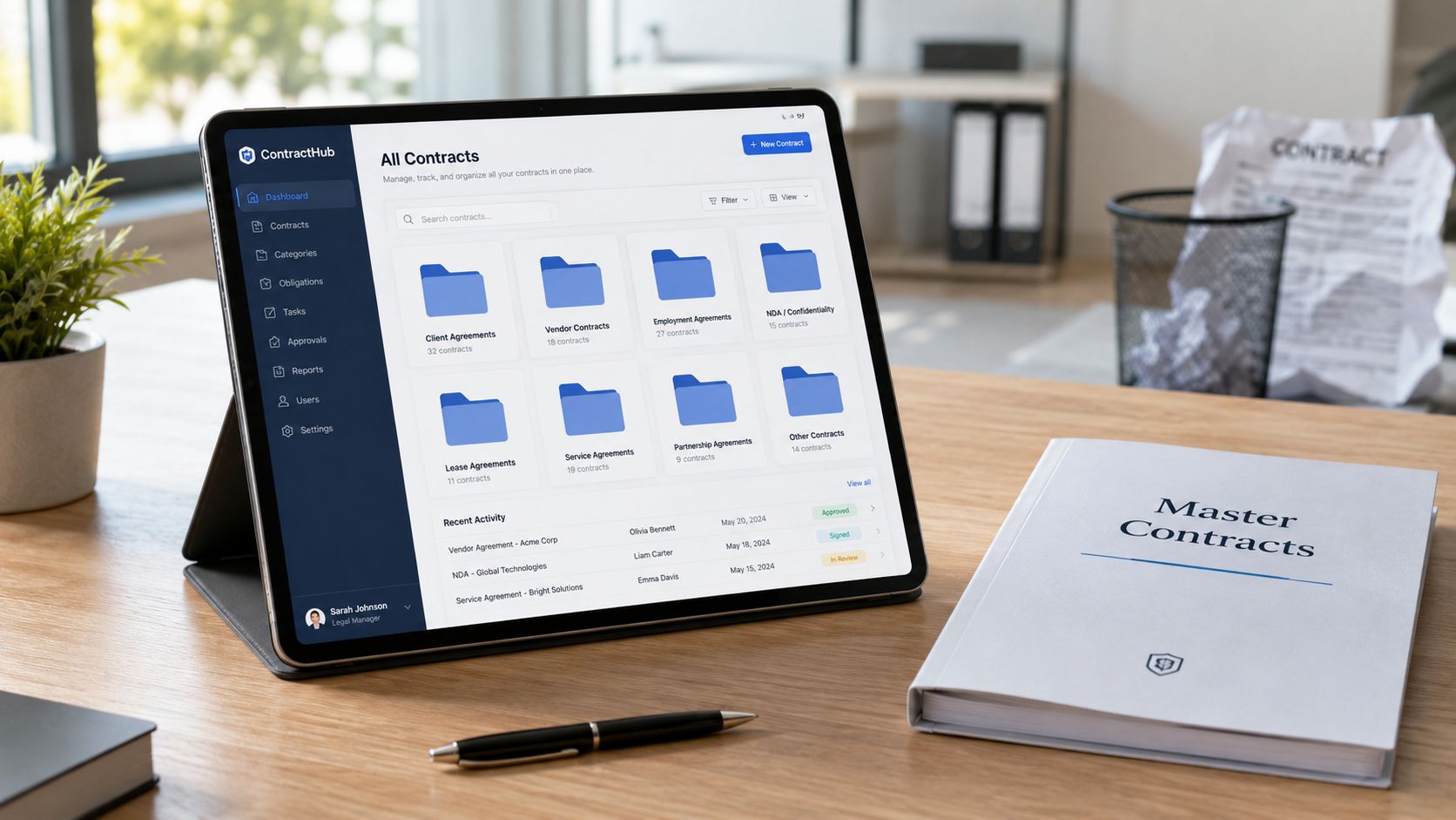 A digital tablet displaying a contract management dashboard on a wooden desk with a pen and notebook.