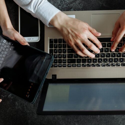 Top view of professionals working on a laptop and tablet, showcasing teamwork and technology.